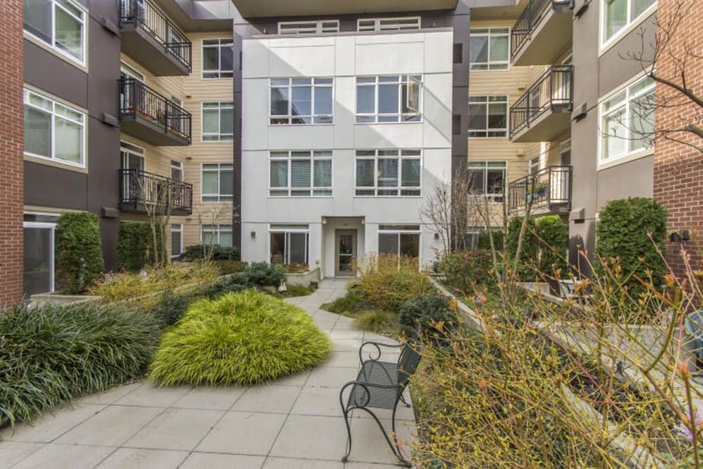 Modern apartment building with a landscaped courtyard and seating area.
