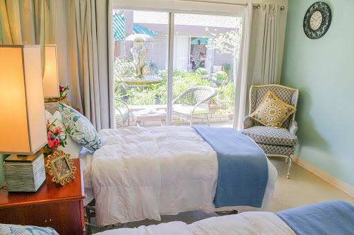 A serene and cozy bedroom featuring twin beds with soft bedding, illuminated by natural light pouring in from the garden-facing window.