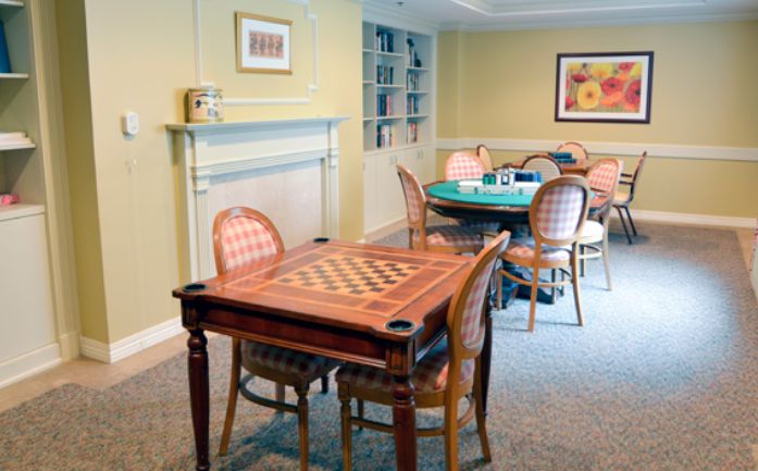 A cozy game room featuring a chess table and a card table with chairs neatly arranged.