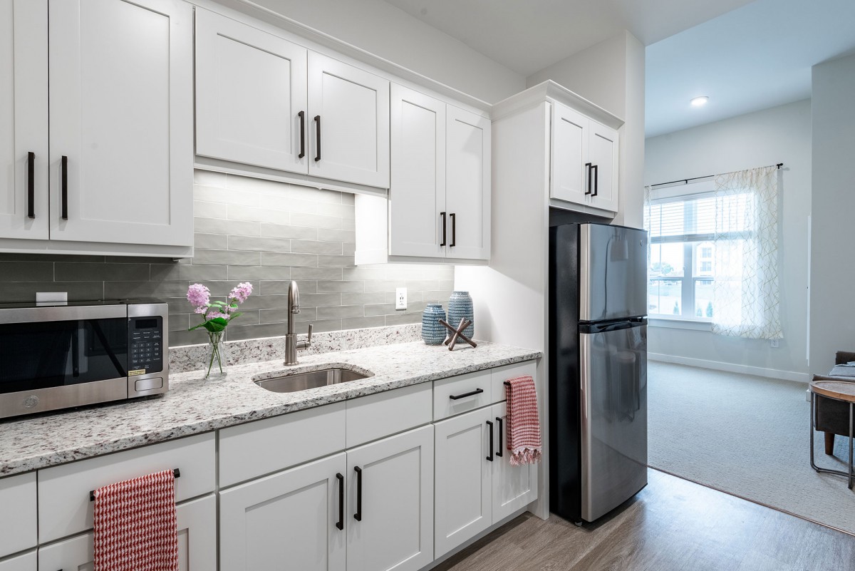 A modern kitchen with white cabinets and stainless steel appliances.