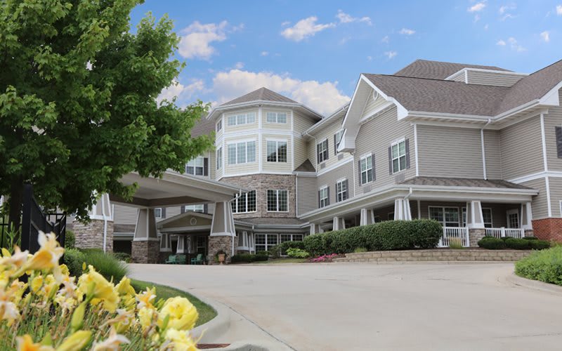 A modern residential building with a beautifully landscaped exterior under a clear blue sky.