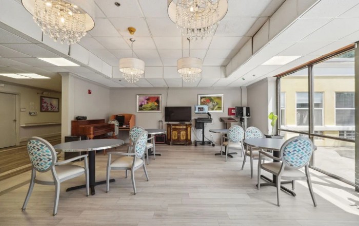 A modern dining room with chandeliers, tables, and chairs on a wooden floor.
