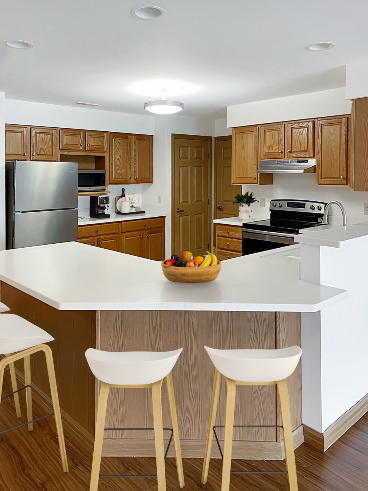 A modern kitchen with wooden cabinets, a large countertop, and bar stools.