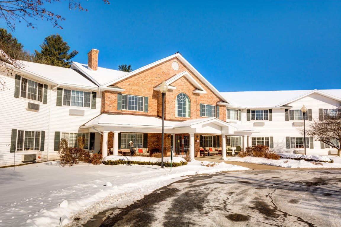 A snow-covered building with a brick facade and a clear blue sky.