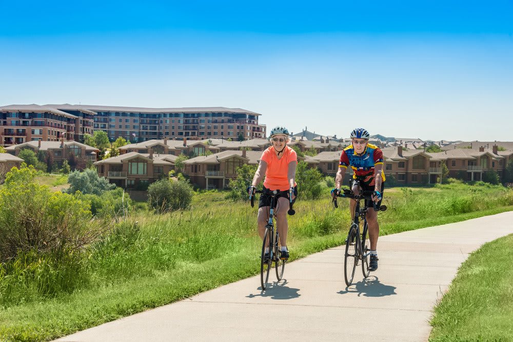 Two people cycling on a sunny day along a scenic path.