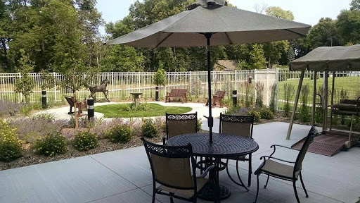 A serene outdoor patio area featuring a table with chairs under an umbrella, overlooking a garden.