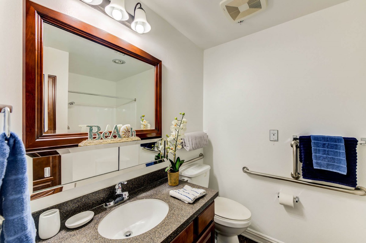 A well-organized bathroom with a sink, mirror, and toilet, featuring modern lighting and decorative elements.
