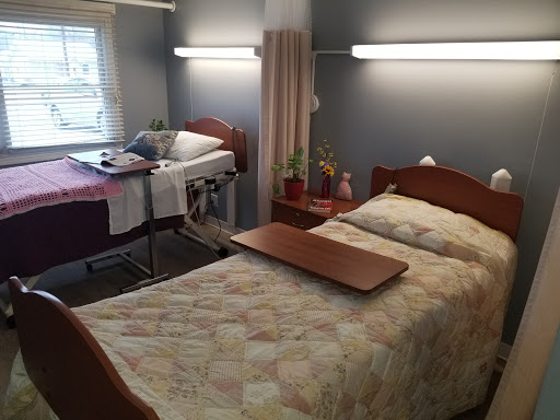 A well-arranged hospital patient room featuring two beds and a warm atmosphere.