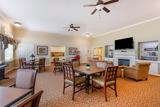A cozy indoor seating area with tables, chairs, a television, and a fireplace.