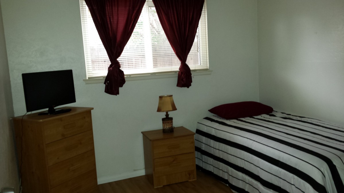 Simple bedroom with a bed, nightstand, and lamp.