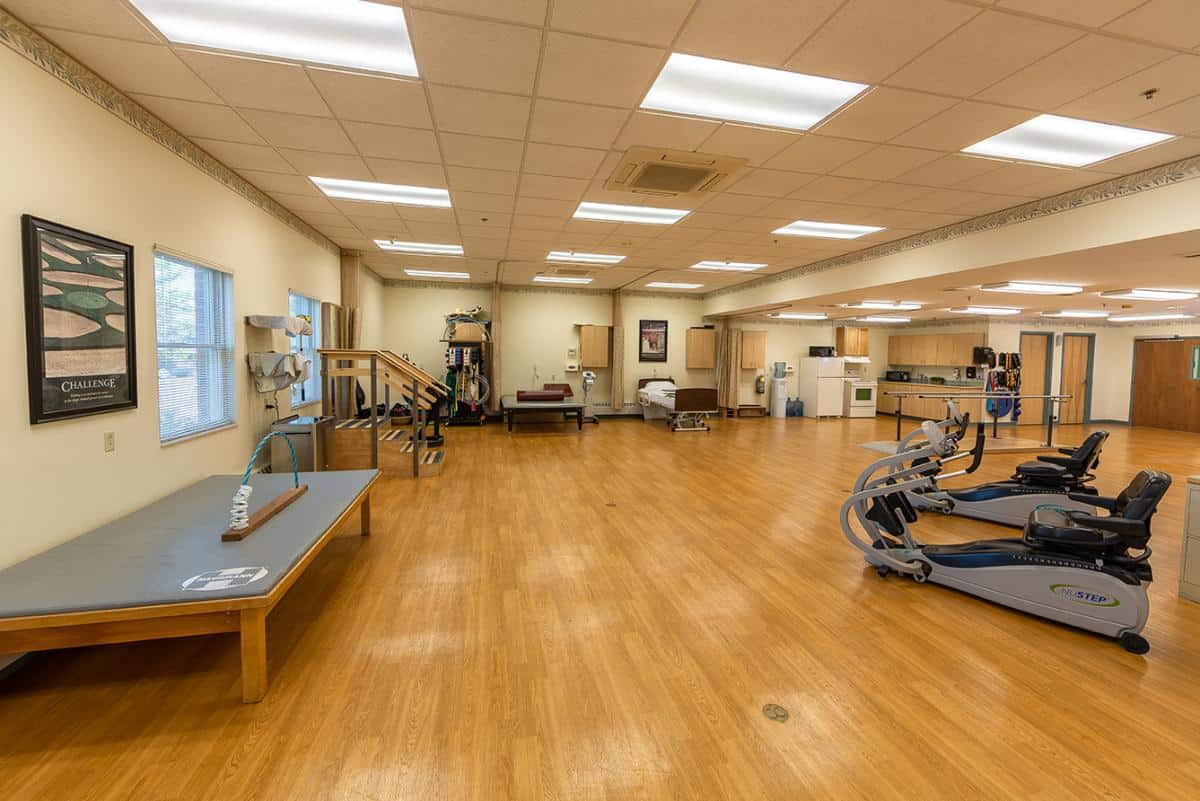 A spacious rehabilitation and therapy room equipped with exercise machines and a wooden floor.