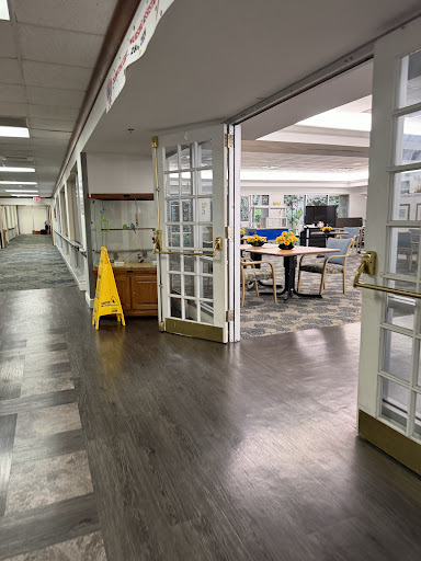 A view of an office corridor leading to a workspace with a cleaning sign.