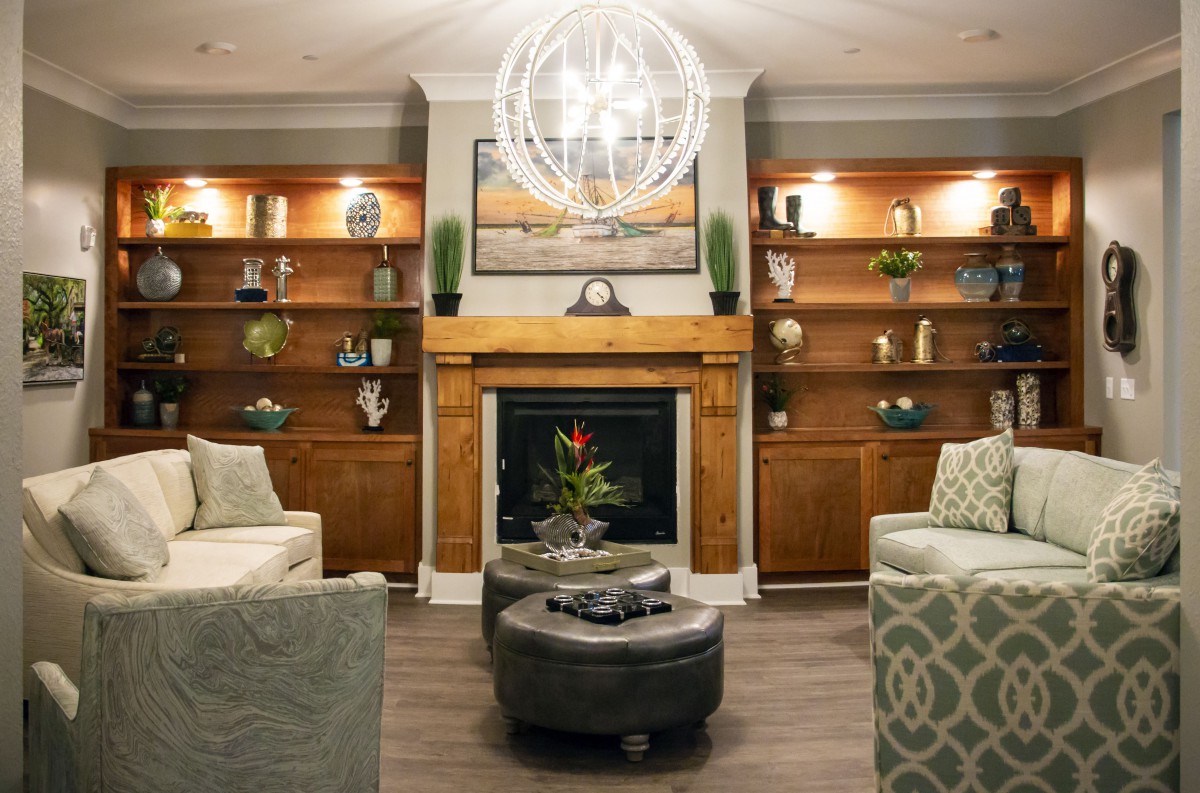 A modern living room featuring a central fireplace, elegant shelving, and comfortable seating with a statement chandelier.