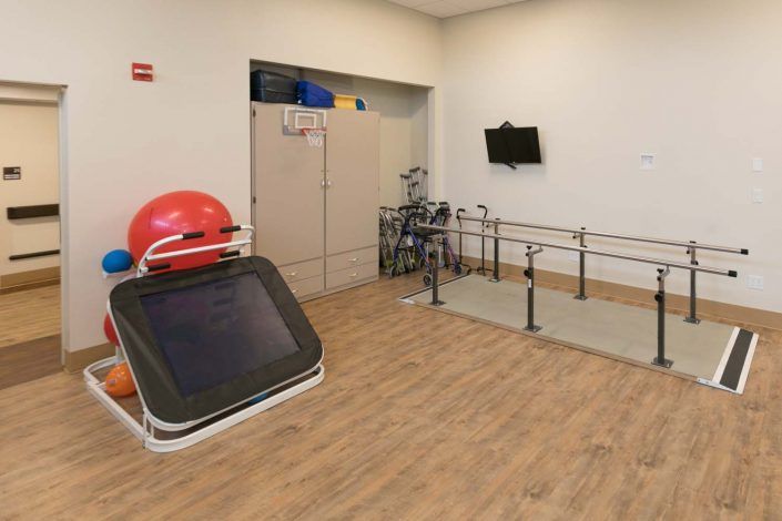 A rehabilitation room equipped with parallel bars and exercise equipment.