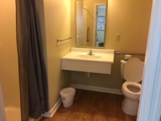 A small bathroom featuring a sink, toilet, and shower area.