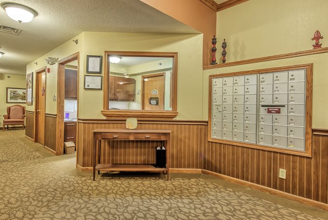 A cozy lobby area featuring wood paneling, a large mirror, and multiple mailboxes.
