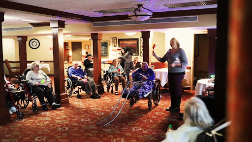 A community event for seniors featuring a presentation, with attendees seated in wheelchairs enjoying the activity.