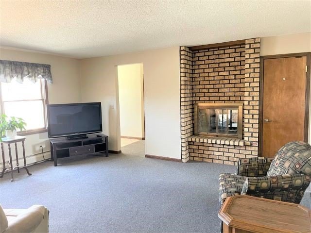 A cozy living room featuring a brick fireplace and a television.
