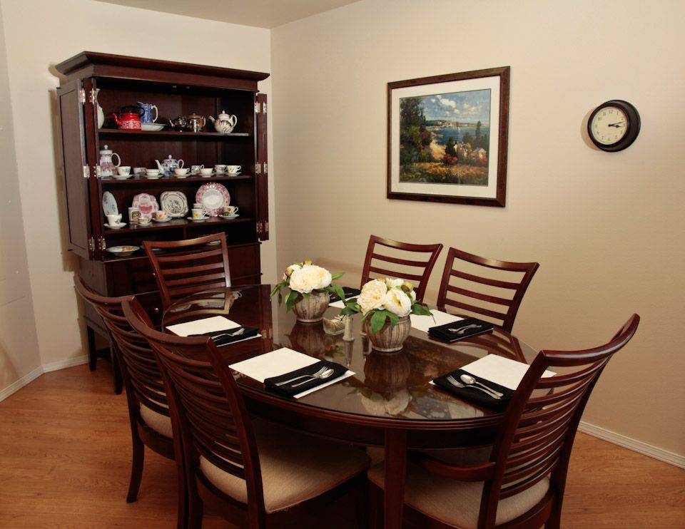 A neatly set dining room with a wooden table and chairs, decorated with flowers and surrounded by tasteful decor.