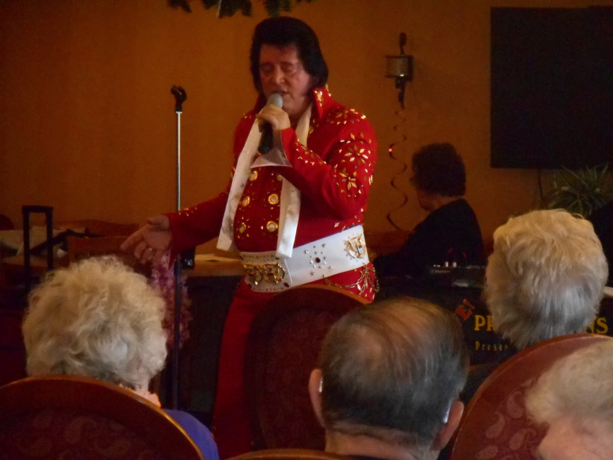 An entertainer dressed in a red costume performs for an audience.