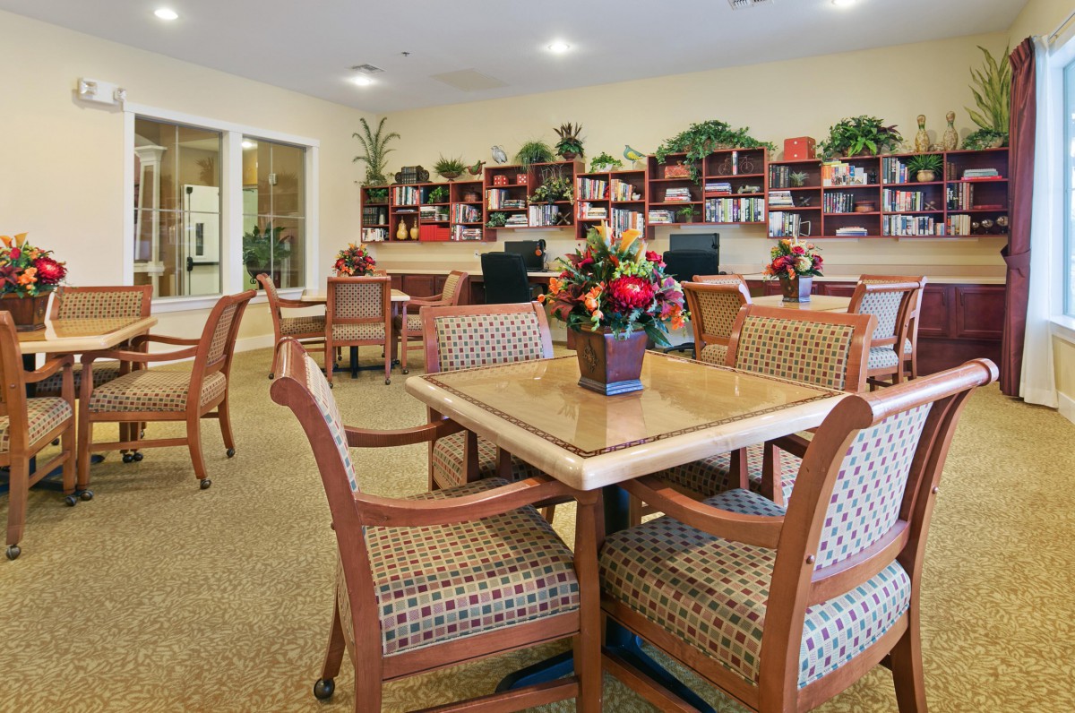 A cozy library reading area with tables, chairs, and bookshelves filled with books.
