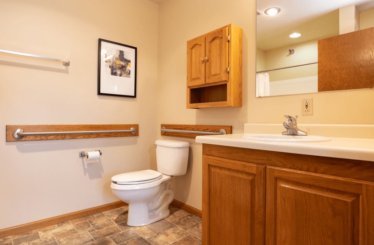 A clean, well-organized bathroom with wooden cabinetry and a tiled floor.