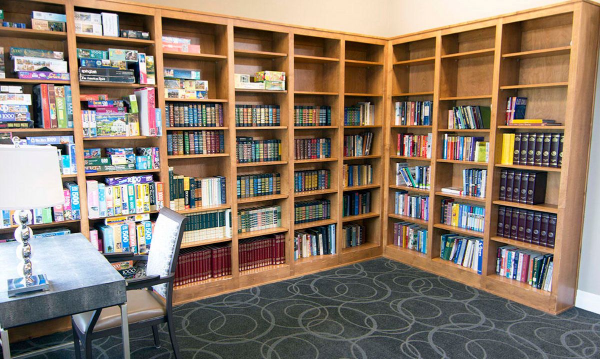 A cozy library corner with wooden bookshelves filled with books and a carpeted floor.