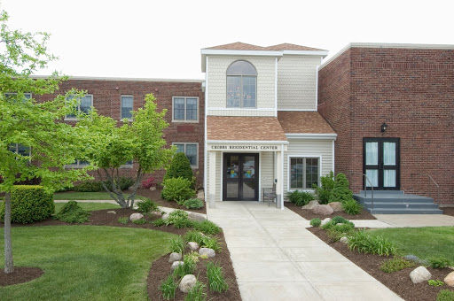 A welcoming front entrance of a residential building surrounded by lush landscaping.