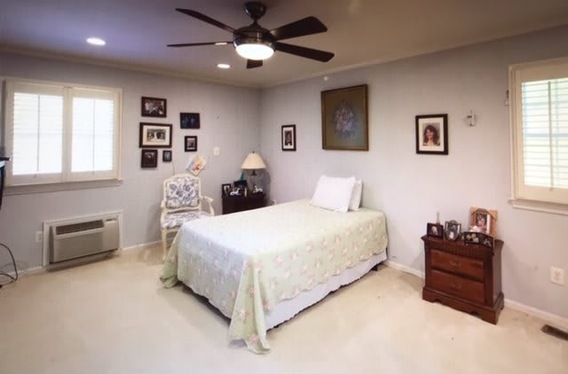 A cozy bedroom with a single bed, ceiling fan, and decorated walls.