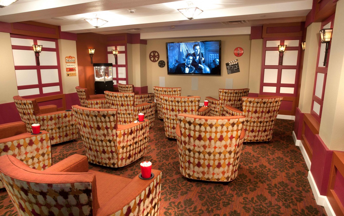 A cozy home theater setup with patterned chairs facing a large television.