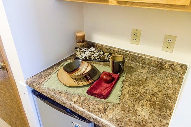 A kitchen counter with decorative dishes, an apple, and candles.