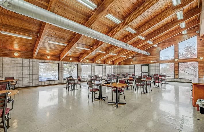 A spacious modern dining area with wooden ceilings and large windows.