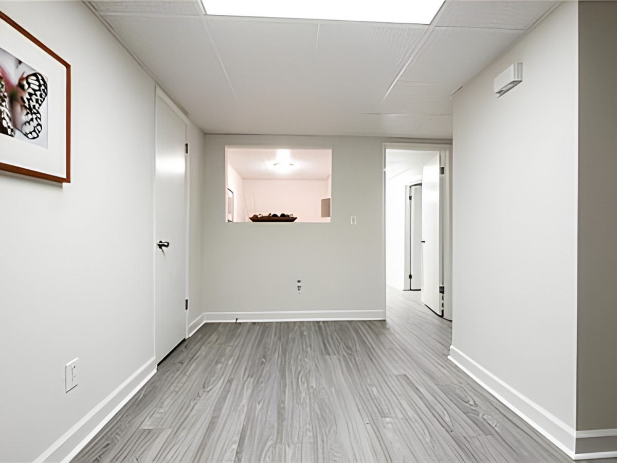 A minimalistic empty room with light gray flooring and white walls.