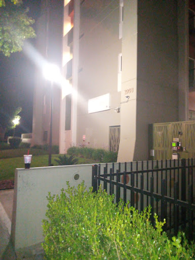 A nighttime view of a building with bright lights and a fenced area.