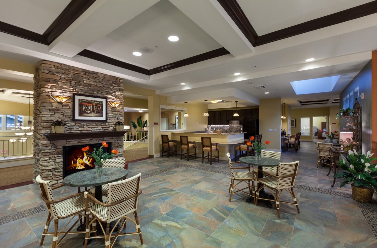 A cozy and modern lobby with a fireplace, seating area, and tables.