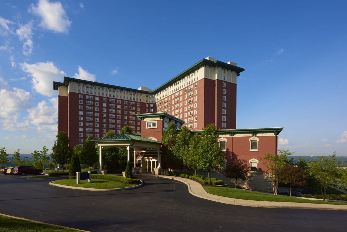 A large hotel building with a brick facade and green rooftops under a clear blue sky.