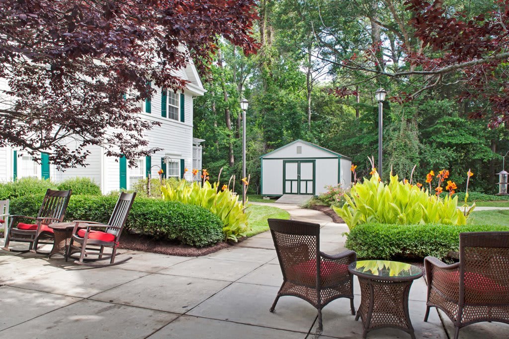 A tranquil backyard patio with outdoor furniture and lush greenery.