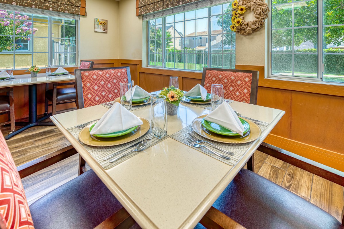 A neatly set dining table in a restaurant with elegant place settings and a window view.