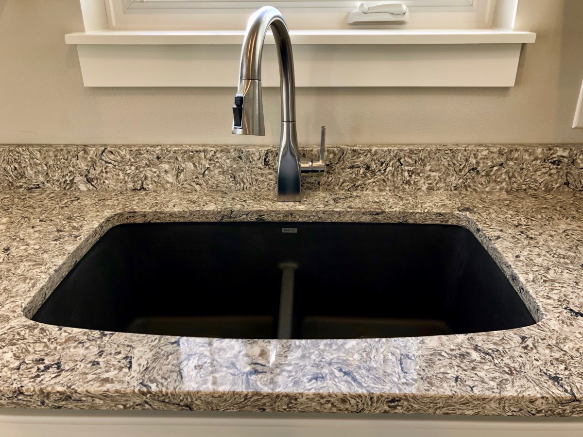 A kitchen sink with a granite countertop and modern faucet.