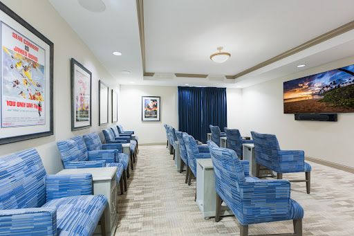 A modern waiting room featuring blue upholstered chairs and decorative artwork on the walls.