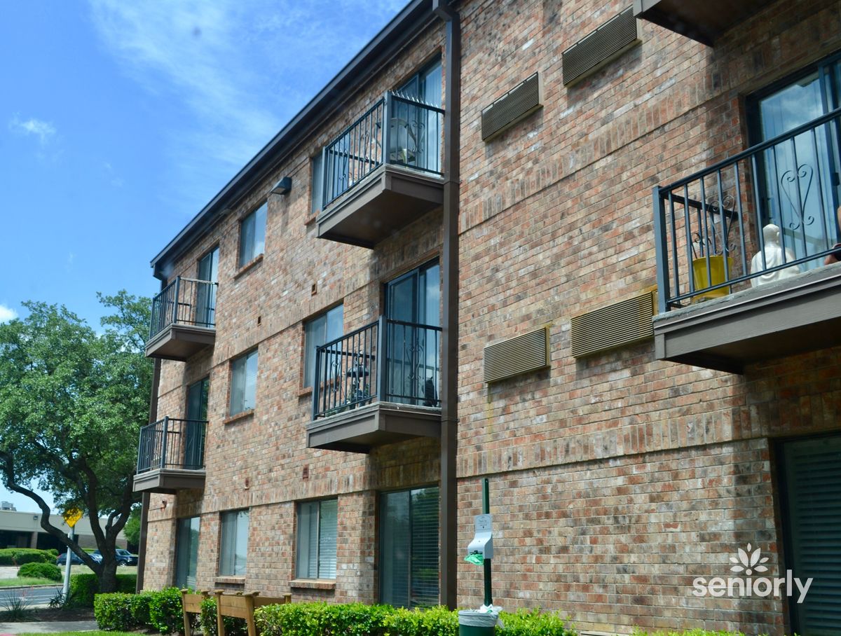 A brick apartment building with multiple balconies under a clear blue sky.