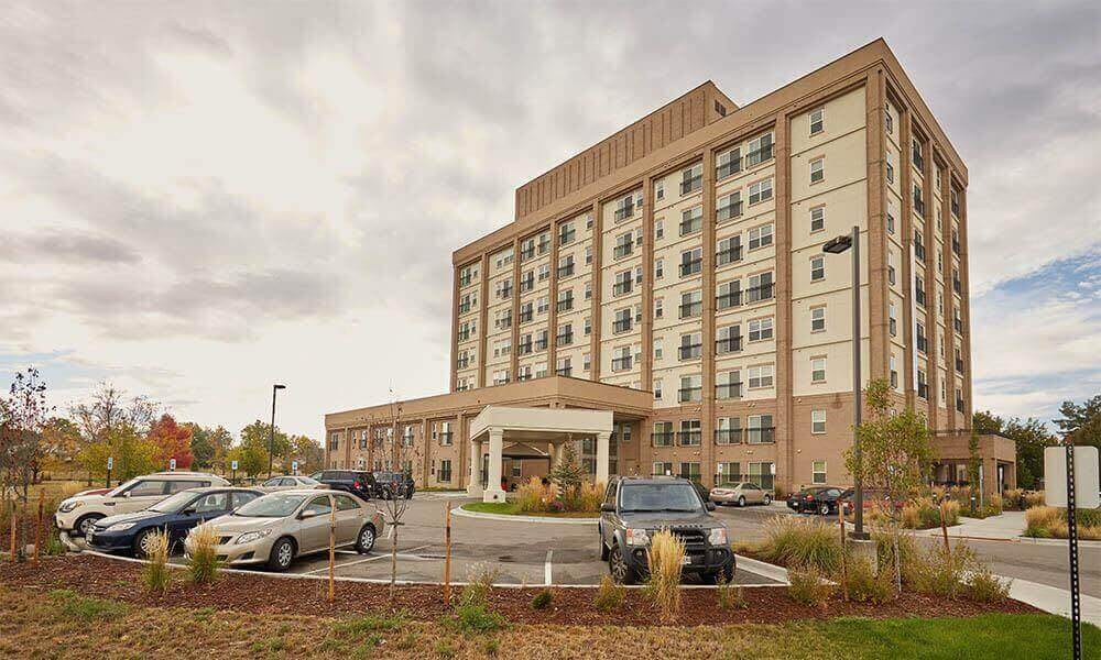 A large hotel building with a parking lot in front under a cloudy sky.