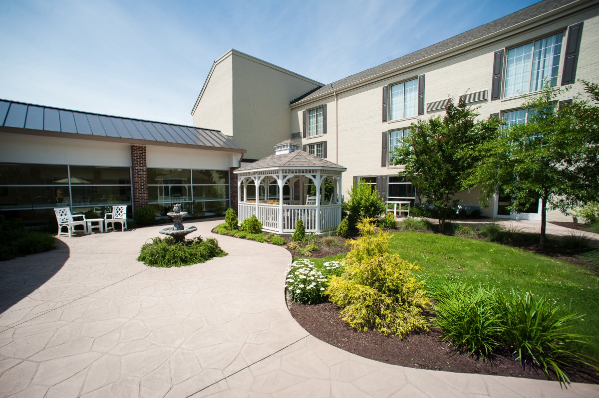 A well-maintained garden area with a gazebo and fountain in front of a modern building.