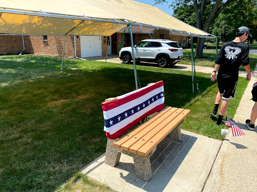 A wooden bench adorned with a red, white, and blue fabric under a tent, perfect for a summer gathering.