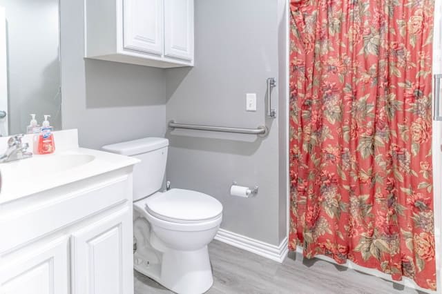 A modern bathroom with a toilet, gray walls, and a floral shower curtain.