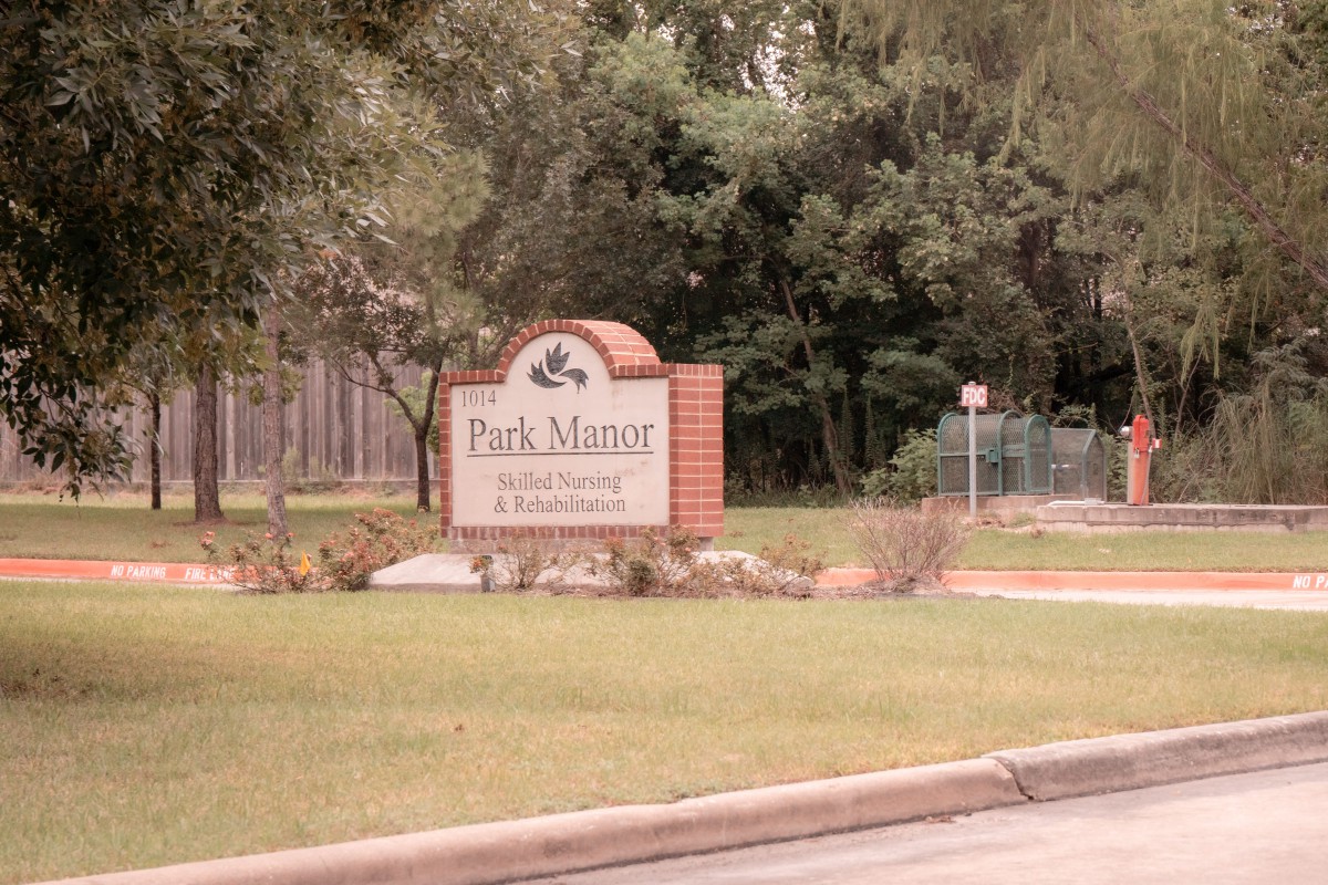 A sign at the entrance of Park Manor, surrounded by greenery and trees.
