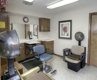 A cozy hair salon interior with styling chairs and a mirror.