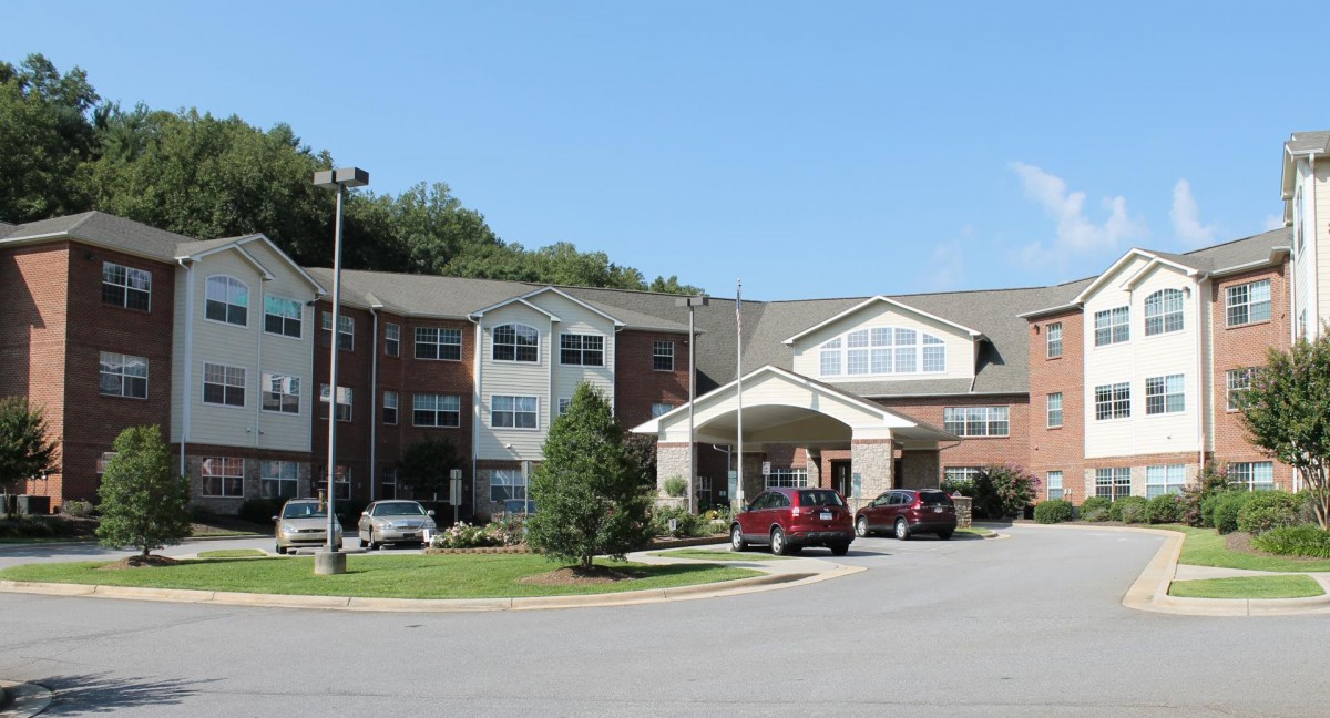 A residential building with parked cars and trees under a clear sky.