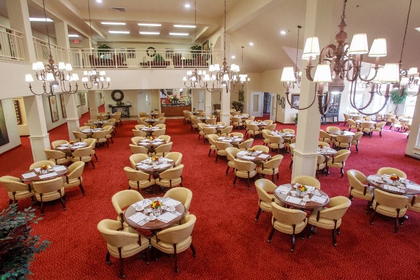 A spacious restaurant dining area with elegantly arranged tables and soft lighting from chandeliers.