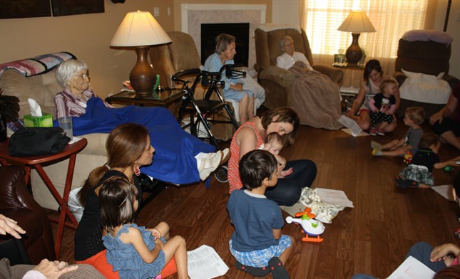 A family gathering in the living room with adults and children spending time together.